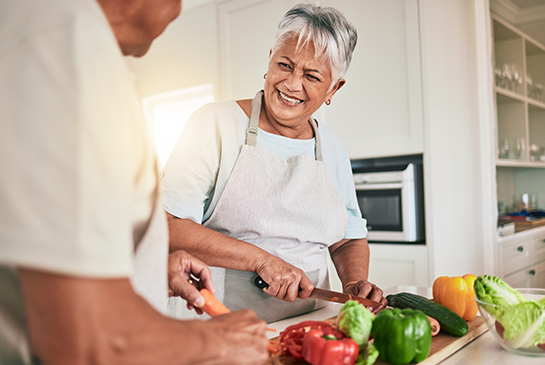 Women cutting vegetables in kitchen.